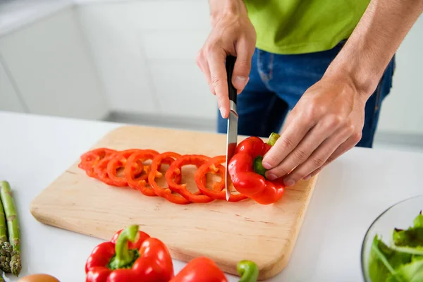 Foto ritagliata giovane uomo che cucina la colazione affettando paprica rossa con coltello — Foto Stock