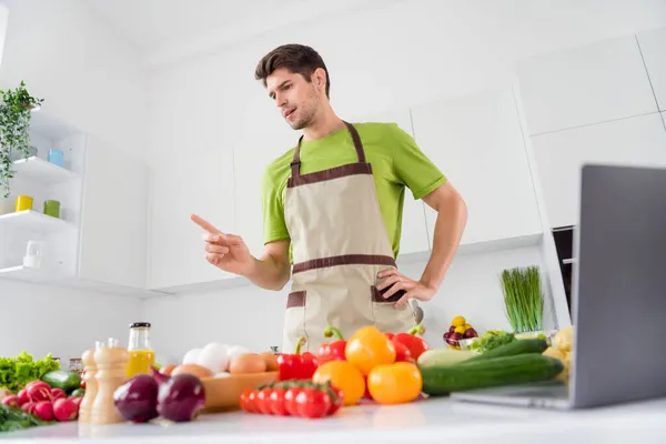 Baixo ângulo vista retrato de cara atraente preparando refeição doméstica fresca escolhendo legumes em casa de cozinha branca clara dentro de casa — Fotografia de Stock