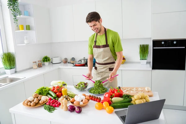 Портрет привабливого веселого хлопця, який готує смачний домашній салатний хобі, дивлячись підручник на домашній кухні в приміщенні — стокове фото