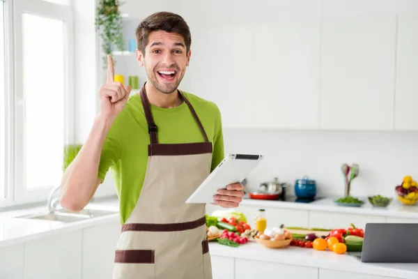 Портрет привабливого веселого хлопця, який готує вечерю, використовуючи пристрій чудової ідеї хобі на домашній кухні в приміщенні — стокове фото