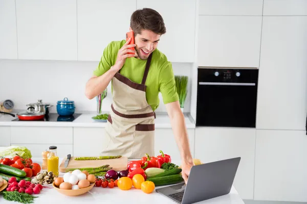 Retrato de cara alegre atraente cozinhar jantar doméstico falando por telefone assistindo vídeo lição em casa cozinha dentro de casa — Fotografia de Stock