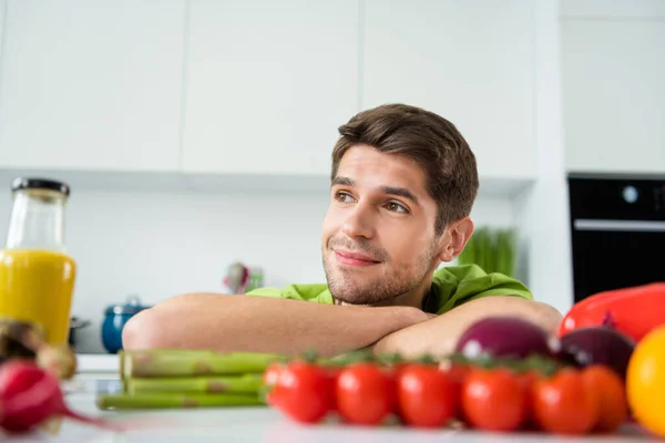 Фотопортрет молодого чоловіка, який готує мрійливий поблизу помідорів овочі — стокове фото