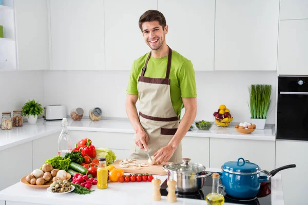 Çekici, yetenekli adamın portresi lezzetli yemekler pişiren lezzetli sosis günü açık beyaz mutfak evinde geçiyor. — Stok fotoğraf