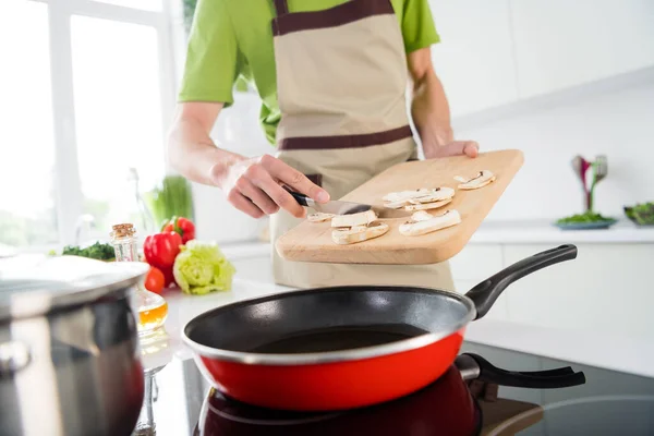 Gehakte foto koken man toevoegen van gesneden champignons op koekenpan — Stockfoto