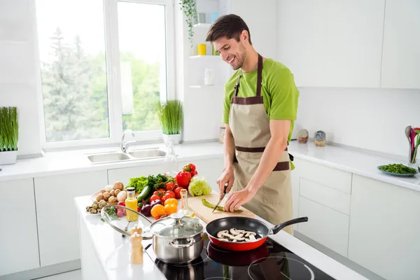 Çekici, neşeli bir adamın portresi ev mutfağında ev yemeği pişiriyor. — Stok fotoğraf