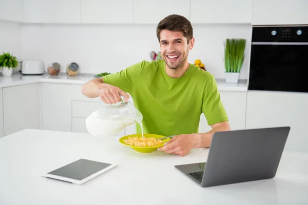 Портрет привабливого веселого хлопця, який готує свіжий швидкий обід, їсть лиття органічного молока на домашній кухні в приміщенні — стокове фото