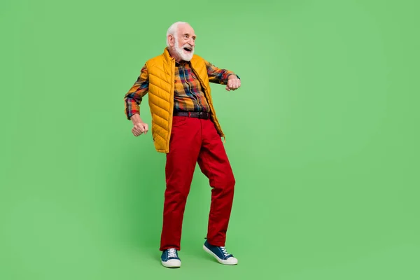 Фото позитивного гарного настрою старший джентльмен носить жовтий жилет, танцює усміхнений ізольований зелений колір фону — стокове фото