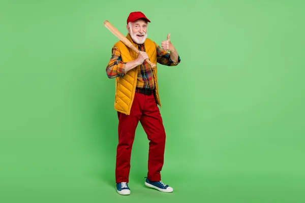 Foto di bel signore anziano indossare giubbotto giallo tenendo pastella mostrando pollice in su sorridente isolato sfondo di colore verde — Foto Stock