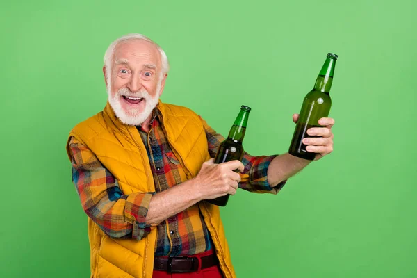 Bild av stilig upphetsad mogen man klädd gul väst leende hålla öl flaskor isolerad grön färg bakgrund — Stockfoto