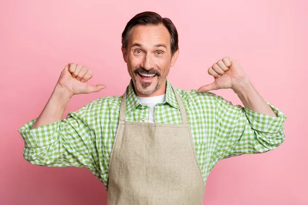 Foto de emocionado impresionado joven vestido de delantal beige camisa a cuadros sonriendo señalando los dedos a sí mismo aislado pastel claro color rosa fondo — Foto de Stock