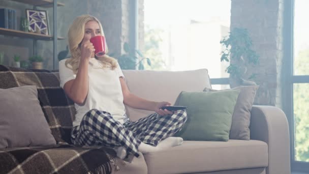 Zrelaksowany pozytywny lady siedzieć kanapa pić kawa oglądać film TV — Wideo stockowe