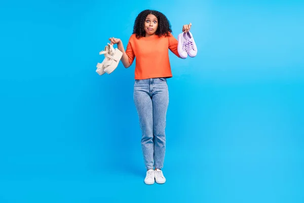 全尺寸的年轻非洲女人的照片决定了买鞋子的销售要独立考虑蓝色背景 — 图库照片