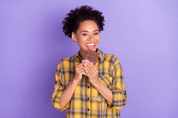 若いアフリカの女の子の写真幸せな正の笑顔は紫の色の背景に隔離されたチョコレートおいしい食事を食べる — ストック写真