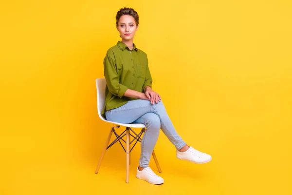 エレガントな魅力的な可愛い女性の写真は椅子に座る緑のシャツジーンズの靴を着用孤立黄色の色の背景 — ストック写真