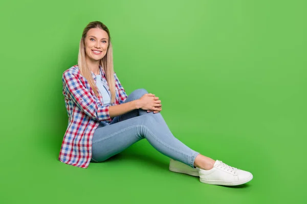 フルサイズプロフィール側の写真の若い女性幸せな正の笑顔座って床に隔離された緑の色の背景 — ストック写真