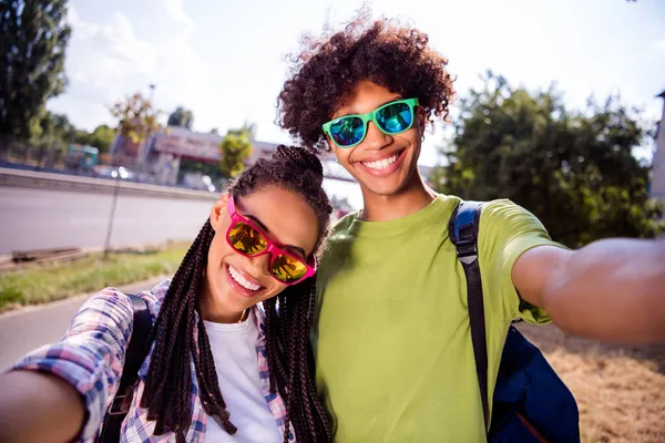 Foto porträtt leende par bär glasögon med selfie leende promenad i staden — Stockfoto