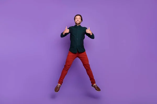 かわいいファンキーな若い男の写真スマートカジュアル服笑顔ジャンプ表示親指アップ孤立した紫色の背景 — ストック写真