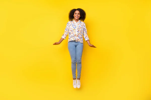 Foto de longitud completa de dulce joven ondulado peinado señora salto usar blusa jeans calzado aislado sobre fondo amarillo — Foto de Stock
