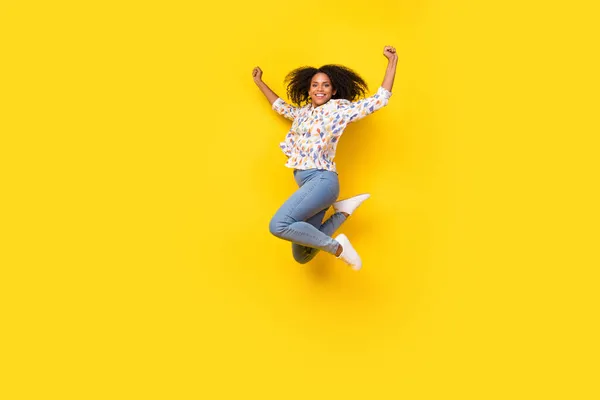 Milenyum kıvırcık, kıvırcık saçlı, atlayan kadının tam boy fotoğrafı sarı arka planda izole edilmiş bluz kotları giyin. — Stok fotoğraf