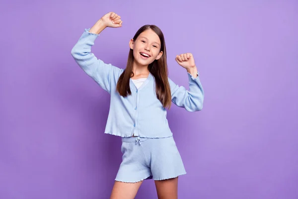 Foto de comemorar morena pequena menina mãos punhos desgaste camisa azul isolado no fundo cor violeta — Fotografia de Stock
