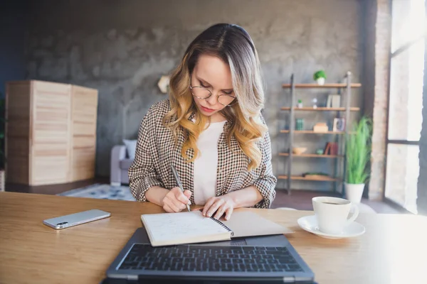 Foto de estricto cabello rubio trabajo dama sentarse escribir notas usar gafas chaqueta marrón en casa solo — Foto de Stock