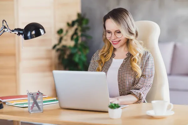 Fénykép dolgozó szőke haj hölgy ülni típusú laptop visel barna kabát szemüveg otthon egyedül — Stock Fotó
