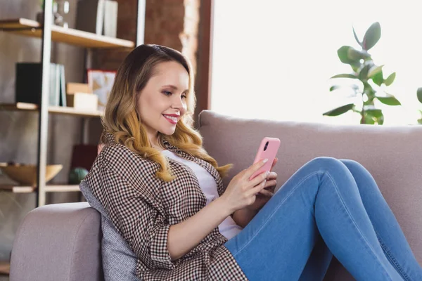 Photo de charmante jeune femme douce porter chemise à carreaux canapé assis tapant dispositif moderne à l'intérieur maison de chambre — Photo