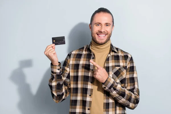 Foto de cara jovem segurar cartão bancário indicar cartão de débito dedo anunciar aconselhar renda isolada sobre fundo de cor cinza — Fotografia de Stock