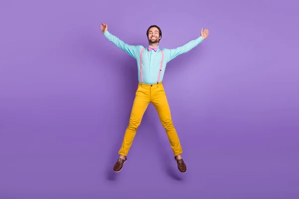 Full length photo of hipster millennial guy jump wear tie suspenders shirt pants sneakers isolated on purple background.