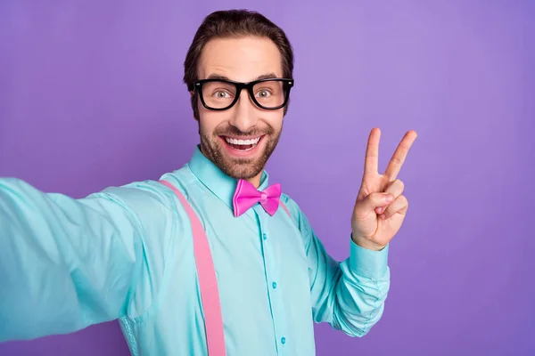 Foto do jovem morena cara mostrar v-sign do selfie usar suspensórios gravata azul camisa óculos isolados no fundo roxo — Fotografia de Stock