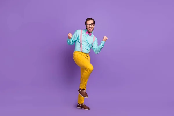 Foto de comprimento total de otimista jovem morena mãos punhos usar suspensórios gravata camisa óculos calças sapatos isolados no fundo violeta — Fotografia de Stock