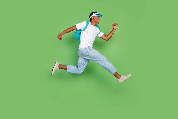 Photo de profil pleine grandeur de funky millennial brunet guy run wear bag t-shirt jeans baskets isolées sur fond vert — Photo