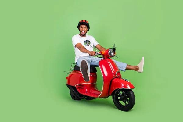 年轻非洲男子驾驶摩托车的全身性侧面照片 与绿色背景相隔离 — 图库照片