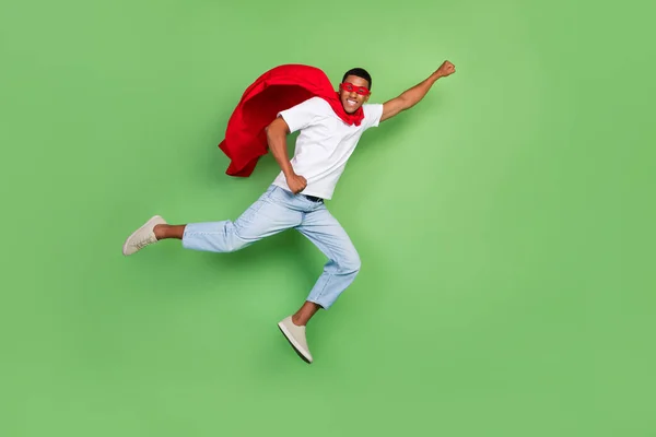 フル長さプロフィール写真の感銘を受けたスーパーマンブルネット男フライ着用勇気マスクTシャツジーンズ履物隔離された緑の背景 — ストック写真