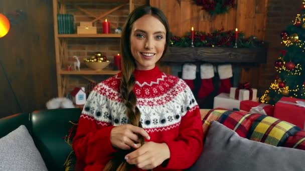 漂亮漂亮漂亮的女士舒适地坐在沙发上做辫子梦圣诞和谐的概念 — 图库视频影像