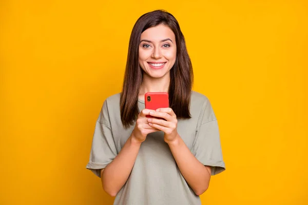 照片上年轻美丽 开朗的女孩用黄色背景的智能手机打字 — 图库照片