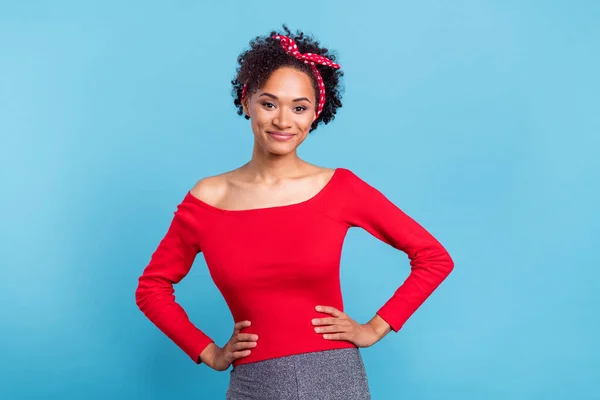 Photo of adorable sweet afro girl wear off-shoulders red shirt arms waist smiling isolated blue color background.