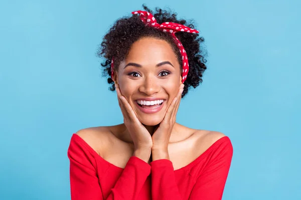 Photo of charming excited afro girl wear off-shoulders red shirt arms cheeks smiling isolated blue color background.