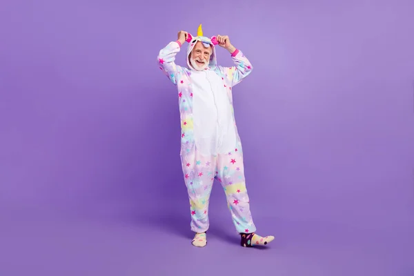 Photo of handsome childish man pensioner unicorn sleepwear dancing walking smiling isolated violet color background — Stock Photo, Image