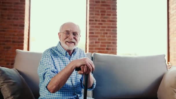快乐积极放松的爷爷享受沙发休息牵着手杖 — 图库视频影像