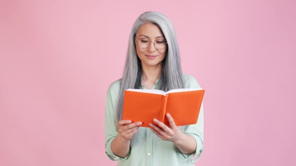Lady geek διαβάσει το βιβλίο απολαμβάνουν αγκαλιά απομονώνονται σε παστέλ χρώμα φόντο — Αρχείο Βίντεο