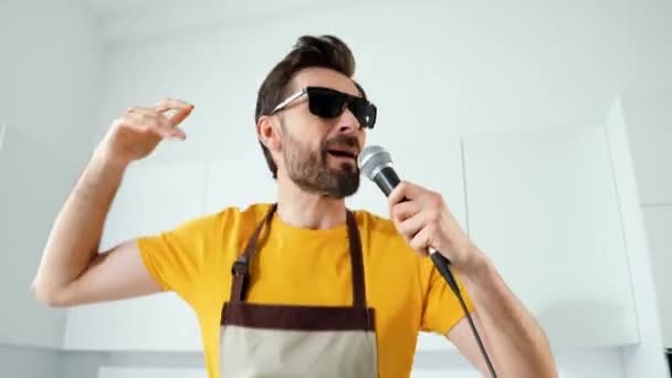 Enerjici adam parti hazırlıyor rüya sahnesi ev mutfağında mikrofon şarkısı söylüyor — Stok video