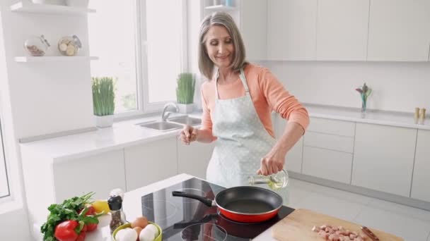 Веселая и дружелюбная леди наливает оливковое масло приготовить картошку фри нарезанный мясной рулет — стоковое видео