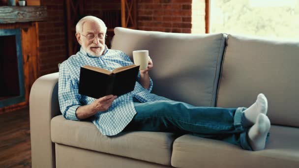 Positivo sonhador vovô segurar livro didático ler desfrutar de café — Vídeo de Stock