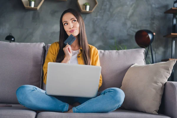 Foto de dulce joven bonita vestida camisa amarilla compras en línea moderno gadget sonriendo en el interior habitación casa —  Fotos de Stock