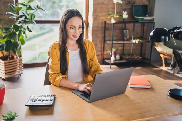 Foto van mooie zoete volwassen vrouw dragen gele shirt bril glimlachen typen modern apparaat binnen huis kamer — Stockfoto