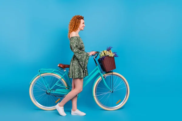 Full size profiel foto van sexy dame rijden fiets dragen jurk sneakers geïsoleerd op blauwe kleur achtergrond — Stockfoto
