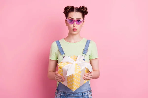 Foto av söt flicka hålla nuvarande rutan skicka luft kyss slitage solglasögon jeans övergripande grön t-shirt isolerad på rosa bakgrund — Stockfoto