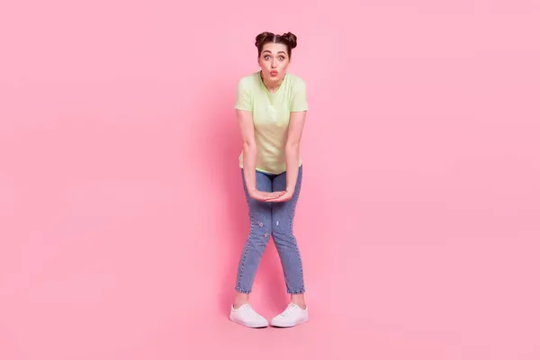 Foto de bonito adorável menina afetuosa tímido enviar ar beijo desgaste verde t-shirt jeans tênis isolado no fundo rosa — Fotografia de Stock