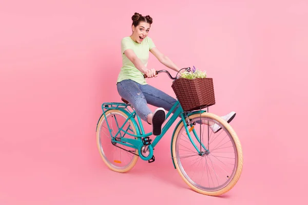 Foto de bicicleta de condução de senhora desportiva animada divirta-se boca aberta desgaste camiseta verde isolado no fundo rosa — Fotografia de Stock